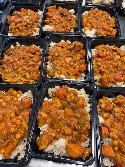 Multiple meal-prep containers filled with white rice topped by orange-brown beef and vegetable curry.