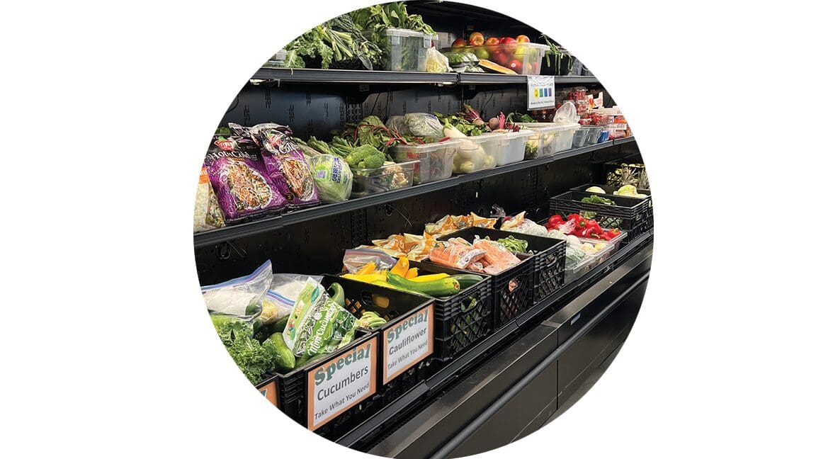 Produce section in a supermarket with bins of fresh vegetables; signs read Special Cucumbers and Special Cauliflower.